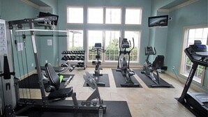 Ein Fitnessstudio mit verschiedenen Trainingsgeräten, darunter Laufbänder, Crosstrainer und Kraftgeräte.
