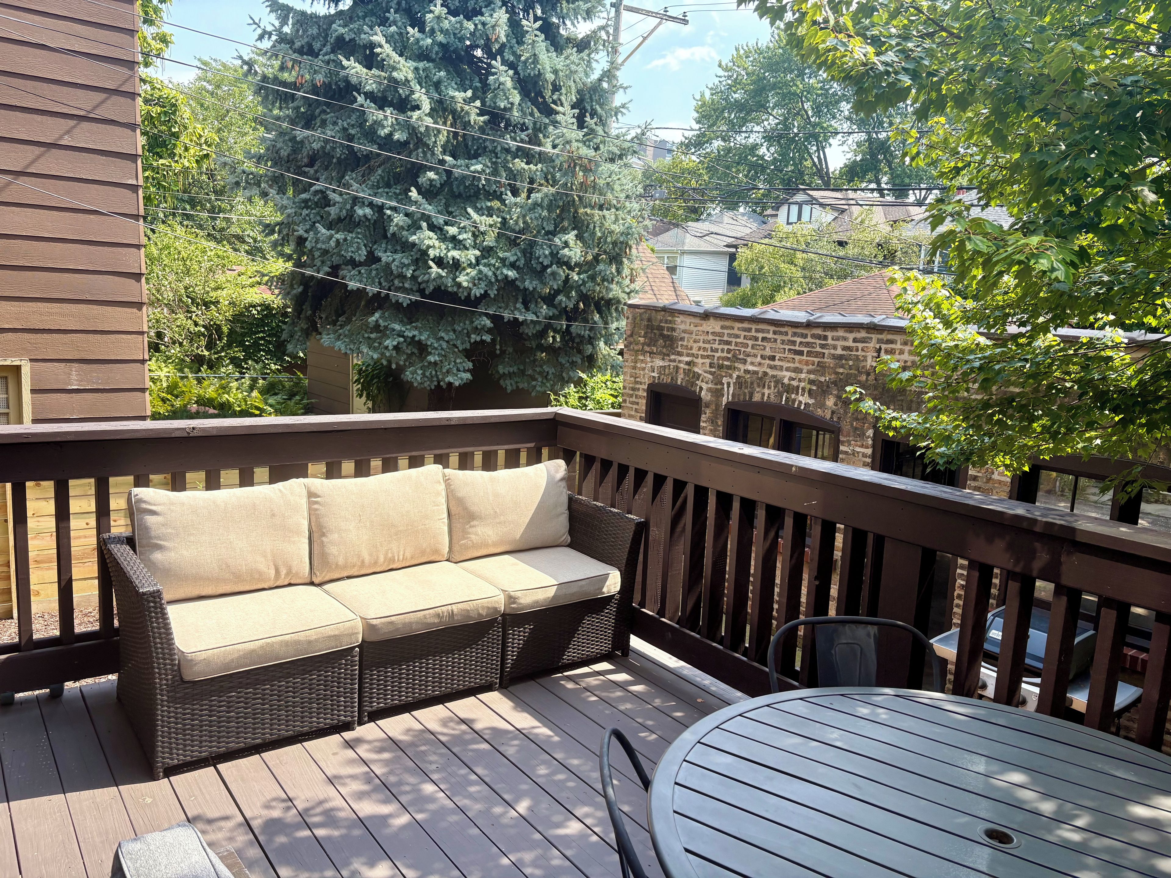 A wooden deck with a wicker sofa and a metal table.