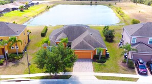 Stroll through a serene neighborhood with a tranquil pond at its heart, surrounded by two-story homes with attached garages and lush lawns.