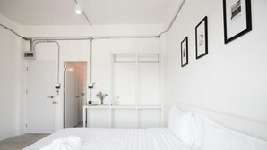 Una habitación de hotel con una cama bien hecha, una ventana con persianas, una puerta y un equipo de aire acondicionado instalado en la pared.