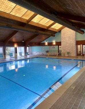 An indoor swimming pool with a wooden ceiling and stone walls.