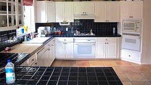 A kitchen with white cabinets, a black tiled backsplash, a microwave, an oven, and a sink. - Family-friendly Golf Course Home near Purgatory. Hot Tub,  BBQ. April Special. (Durango)