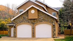 A two-story house with a stone facade, two garage doors, and a small circular window above the garage doors. - Family-friendly Golf Course Home near Purgatory. Hot Tub,  BBQ. April Special. (Durango)