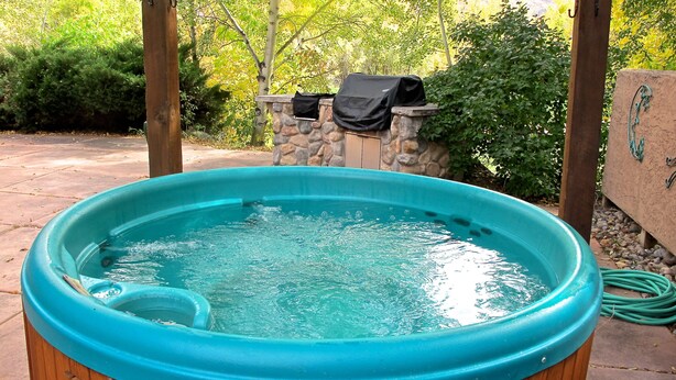 A turquoise hot tub with a stone wall and greenery in the background. - Family-friendly Golf Course Home near Purgatory. Hot Tub,  BBQ. April Special. (Durango)