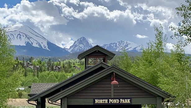 Un edificio nel North Pond Park con una veranda coperta, tavoli da picnic e un braciere.
