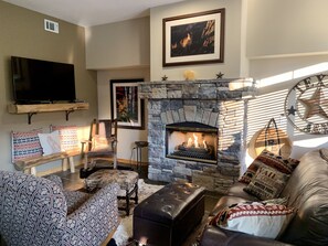 Cozy living room with a fireplace, comfortable seating, and a flat-screen TV.