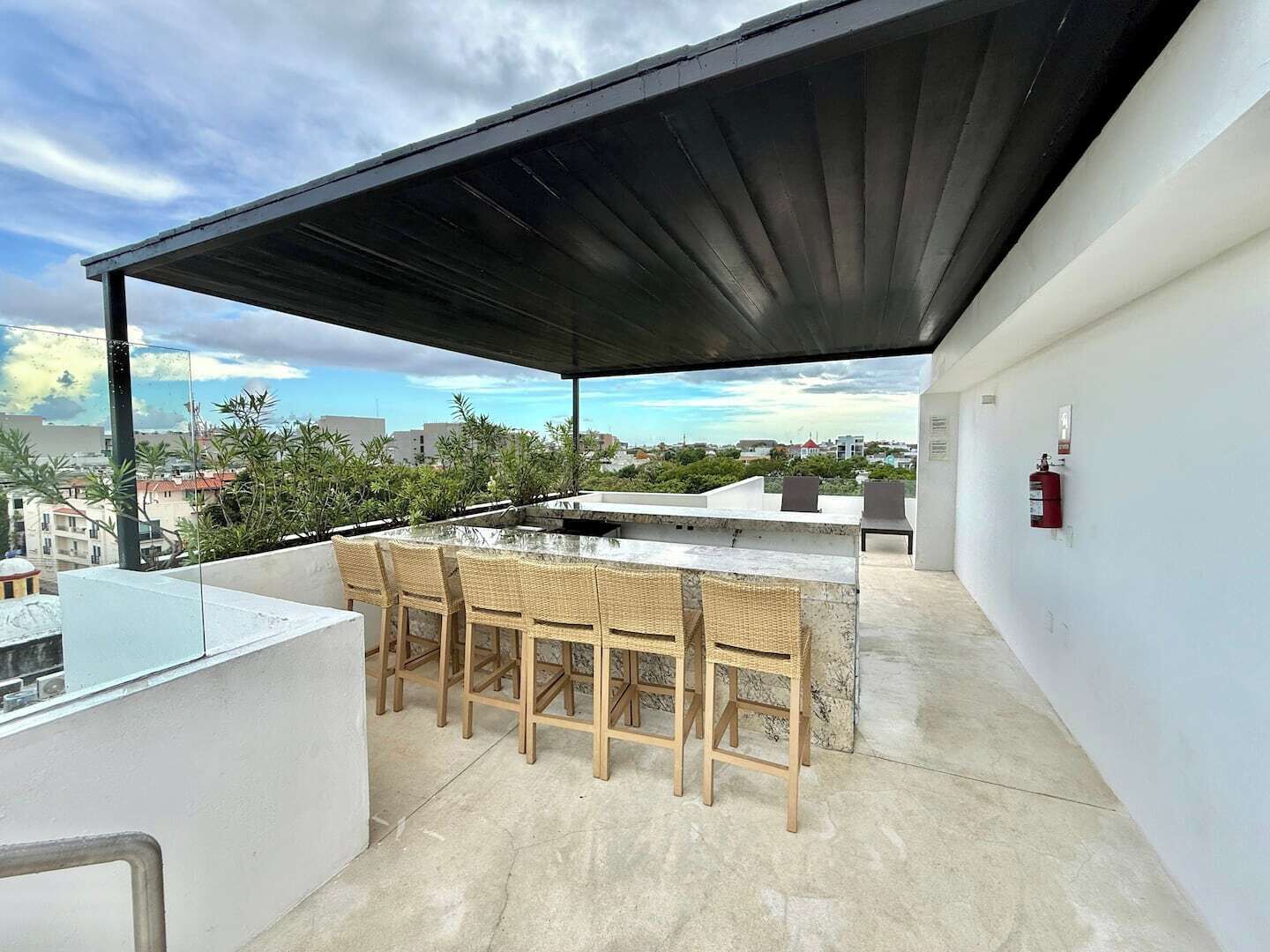 A rooftop terrace with a covered seating area, a bar, and a fire extinguisher.