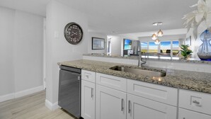 A modern kitchen with granite countertops, stainless steel appliances, and white cabinetry. - Ocean Front 2 Bed 2 Bath With Ocean Front Pool, walk to restaurants (St. Augustine)