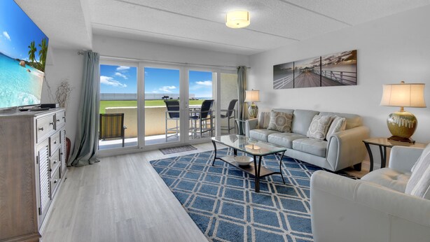 A spacious living room with a large window offering a view of the beach and ocean. - Ocean Front 2 Bed 2 Bath With Ocean Front Pool, walk to restaurants (St. Augustine)
