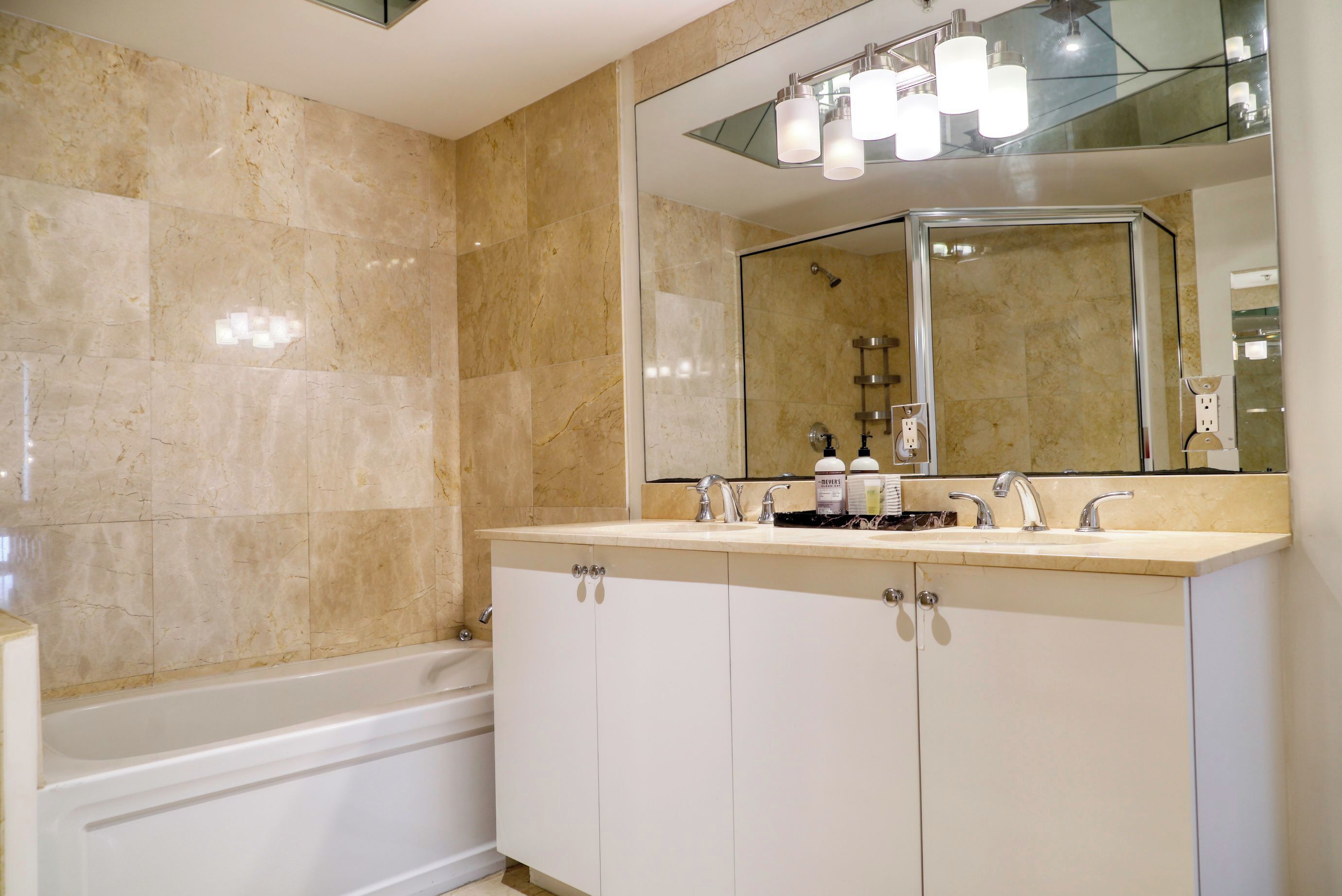 Une salle de bain moderne avec un meuble-lavabo à deux vasques, un grand miroir et une baignoire.
