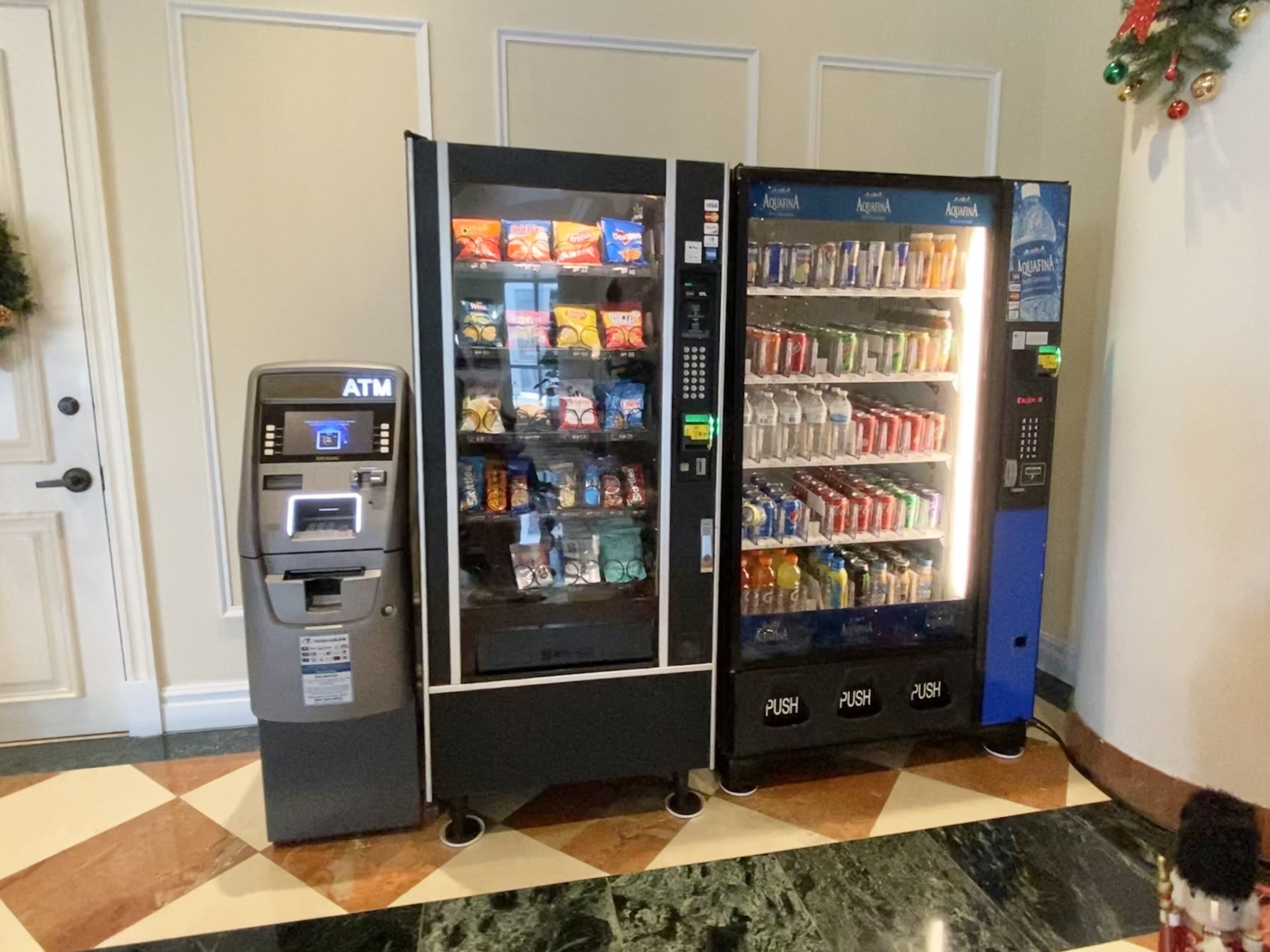 Eine Reihe von Automaten mit Snacks und Getränken, ein Geldautomat und eine Weihnachtsdekoration.