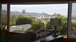A room with a view of a coastal area, a lamp, a starfish decoration, and a sign on the window.