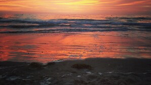 A beach with waves and a sunset.