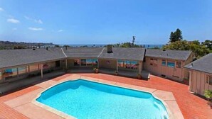 A swimming pool surrounded by houses with a clear view of the ocean.