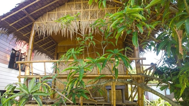 A bamboo-framed structure with a thatched roof, surrounded by lush greenery. - Cast Away  Homestay (Pak Kret)