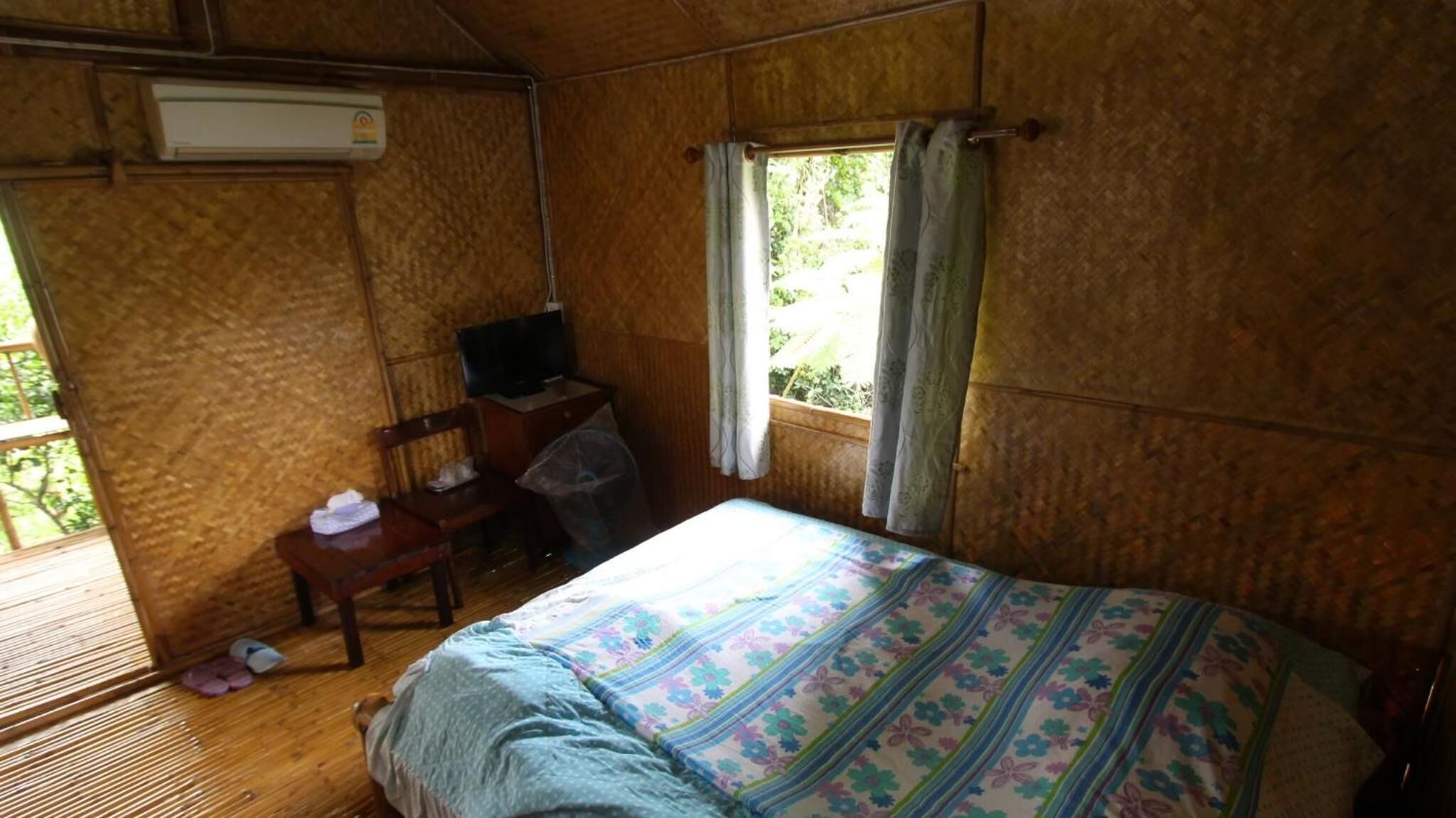 Une pièce comprenant un lit, un bureau, une chaise et une fenêtre avec des rideaux.