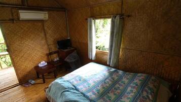 Une pièce comprenant un lit, un bureau, une chaise et une fenêtre avec des rideaux.