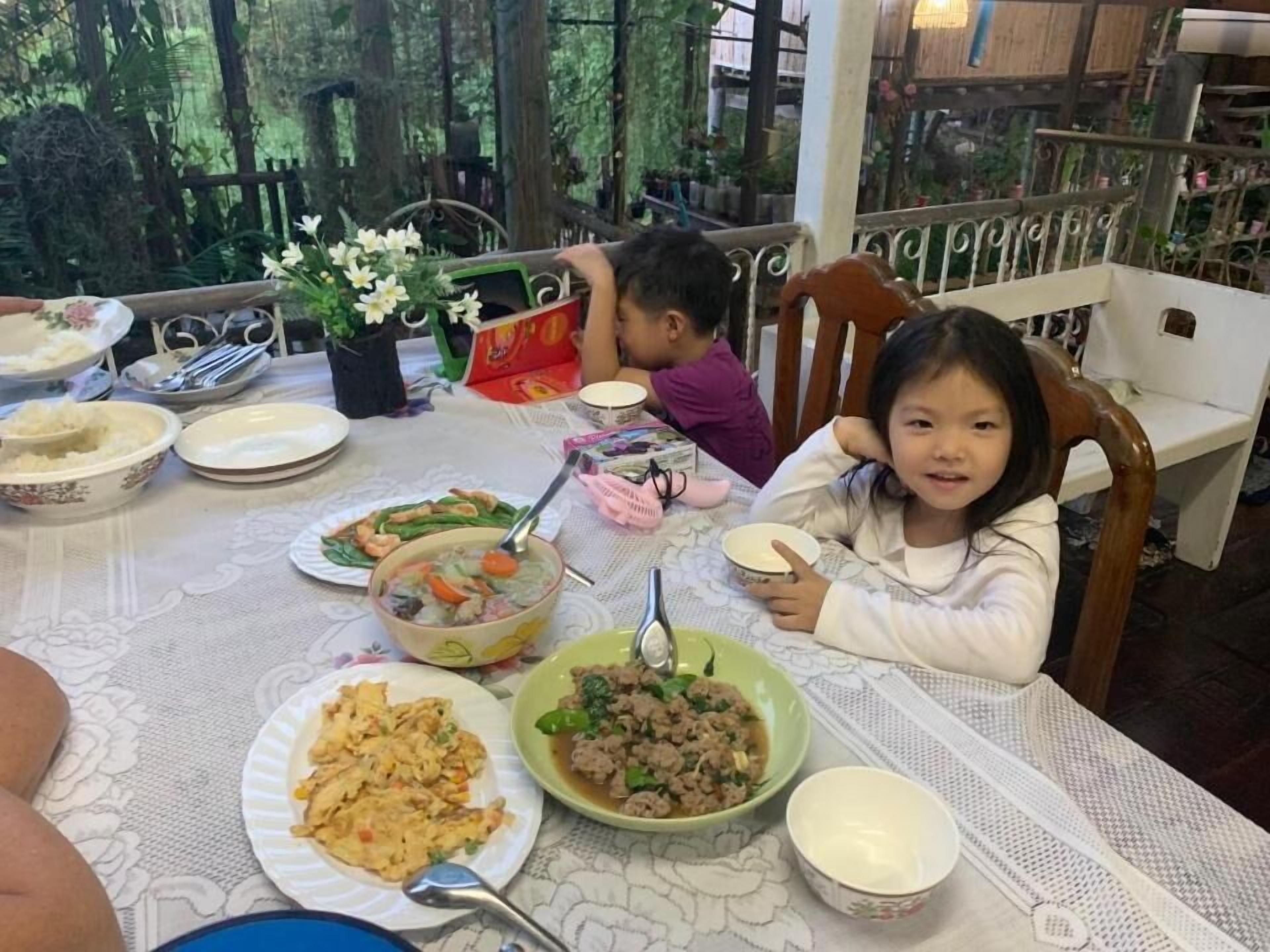 A dining table with various dishes, including a bowl of soup, a plate of stir-fried vegetables, and a bowl of minced meat.