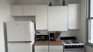 Una cocina compacta equipada con refrigerador, microondas, estufa y alacenas.