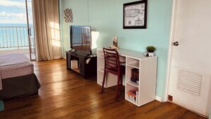 Una habitación con piso de madera, un escritorio con silla, una cama, un ventanal con cortinas y un mapa colgado en la pared.