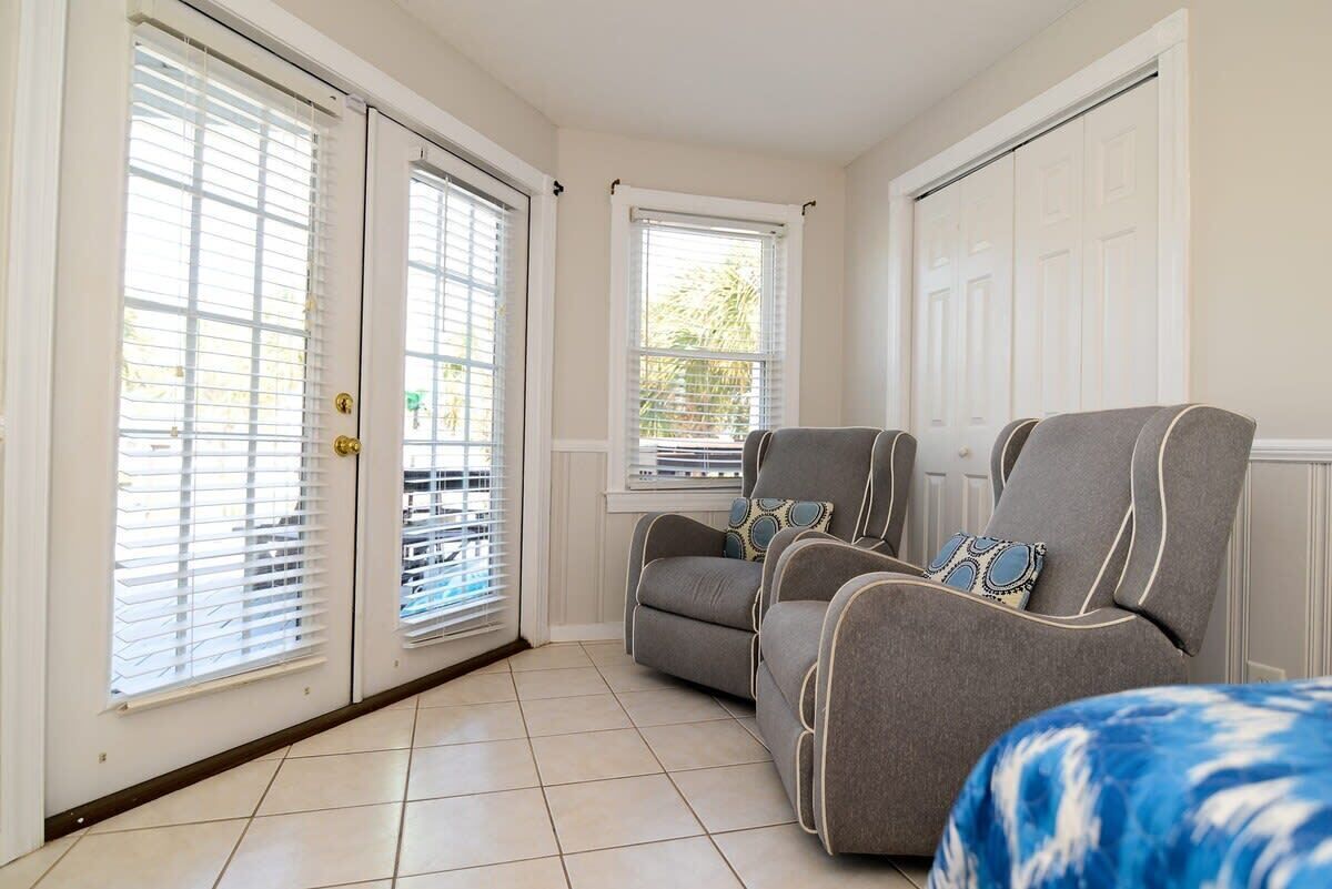 A room with a grey sofa set, a window with blinds, and a door with a handle.