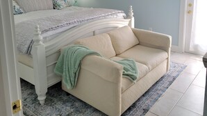 A bedroom with a bed, a ceiling fan, a window with blinds, a couch, and a rug. - Island Retreat: Resort Condo Offering Oasis Pool and Inviting Tiki Bar (Pensacola)