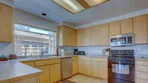 A kitchen with wooden cabinets, a stainless steel microwave, a dishwasher, and a large window. - Amber Sunset - Views! Spacious, Light Bright, Gorge-ous Views! (Mosier)