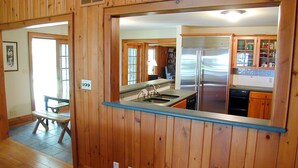A wooden-paneled kitchen with a stainless steel refrigerator, a sink, and wooden cabinets. - Beautiful Lake House, 6 BR, 5 BA, 3500 SF, private beach, wrap around porch. (Fort Erie)