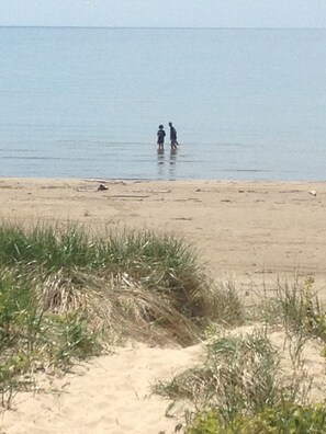 A beach with two people standing in shallow water.