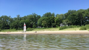 A calm lake with a sailboat and a sandy beach. - Beautiful Lake House, 6 BR, 5 BA, 3500 SF, private beach, wrap around porch. (Fort Erie)