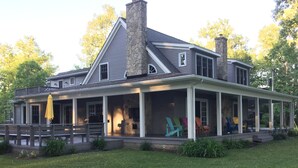 A two-story house with a covered porch, stone chimney, and a grassy yard. - Beautiful Lake House, 6 BR, 5 BA, 3500 SF, private beach, wrap around porch. (Fort Erie)