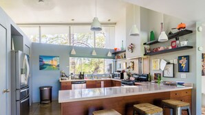 Une cuisine moderne dotée d’un grand îlot central, d’appareils électroménagers en acier inoxydable et de tabourets de bar.