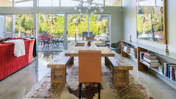 Un salon moderne avec une grande table à manger, un canapé rouge et une bibliothèque.