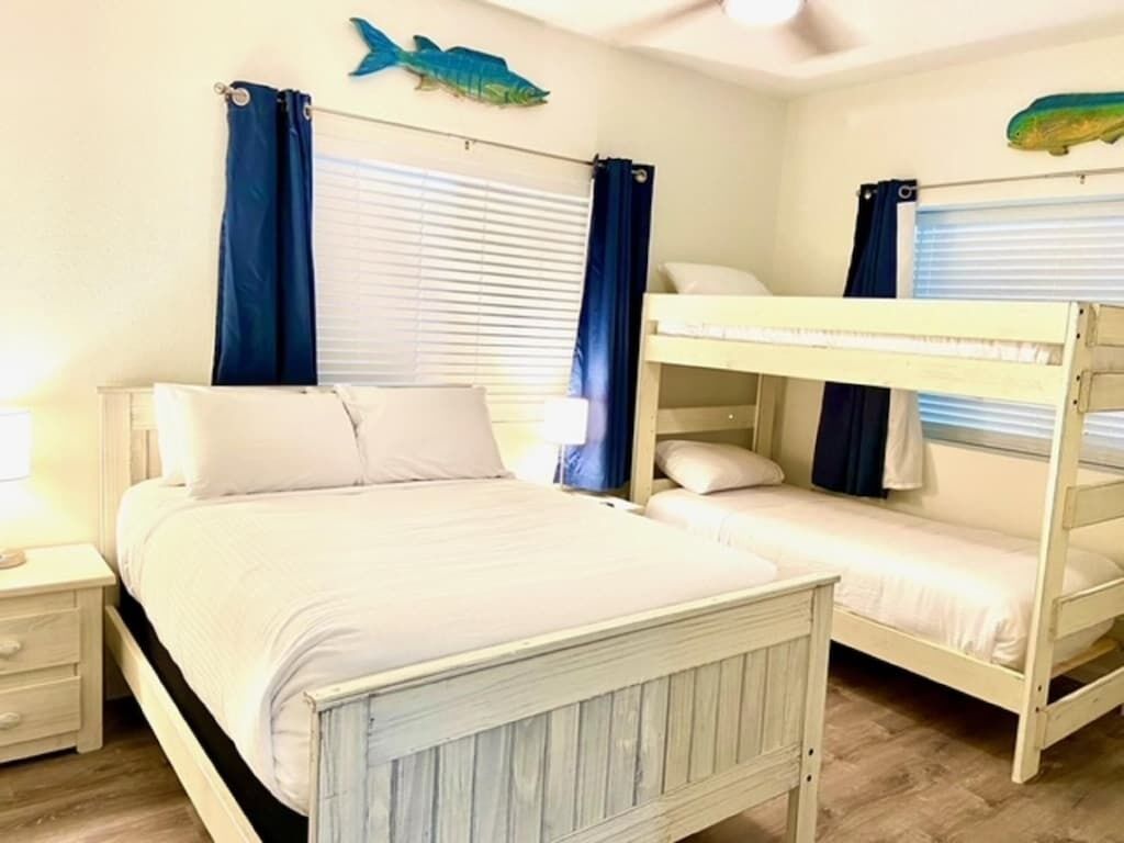 Une chambre avec un lit simple, une table de chevet, une fenêtre avec des rideaux et un lit superposé.