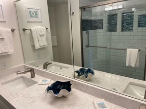 Un bagno con un grande specchio, due lavandini e una zona doccia.