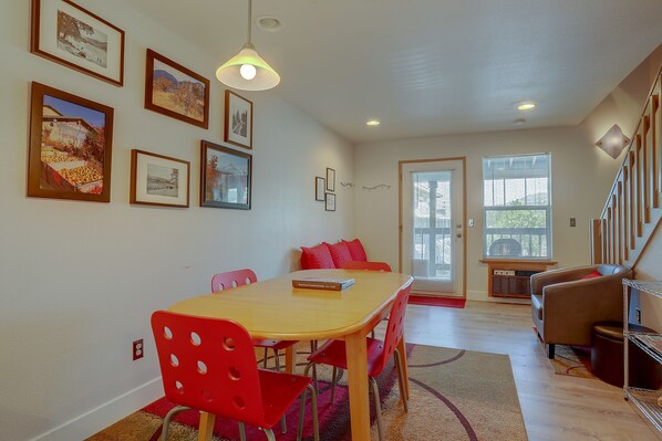 A dining area with a wooden table and red chairs, a staircase, and a door leading outside.