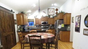 A kitchen with wooden cabinets, a dining table with chairs, and a refrigerator.