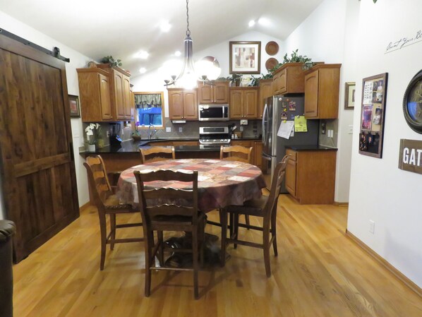 A kitchen with wooden cabinets, a central island, and a dining table with chairs.