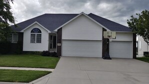 A single-story house with a garage, a small front yard, and a basketball hoop.