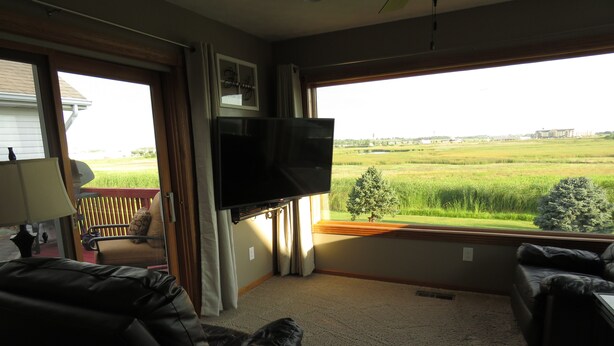 A living room with a flat-screen TV mounted on the wall, a sofa, and a chair.