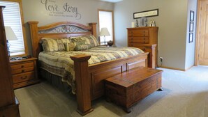 A bedroom with a wooden bed, a nightstand, a dresser, and a wall with motivational quotes.