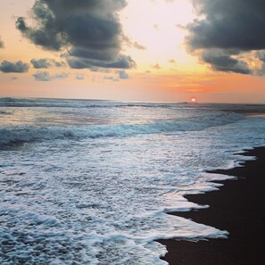 Une plage avec des vagues et un coucher de soleil.