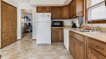 A kitchen with wooden cabinets, a refrigerator, a microwave, and a sink.