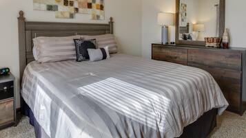 A neatly made bed with a striped bedspread, a wooden headboard, and a bedside table with a lamp.
