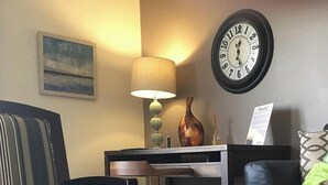 Un saló ben il·luminat amb un sofà, un rellotge i una làmpada. Un senyal indica que la ubicació es troba a la millor i més segura zona de la ciutat a l'est de l'autopista Belt des de St. Joseph Lodging.