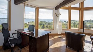 Et moderne kontor med et skrivebord, en stol og store vinduer med et smukt udsyn.