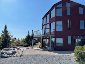 Un bâtiment moderne doté d’un balcon, de grandes fenêtres et d’une allée gravillonnée.