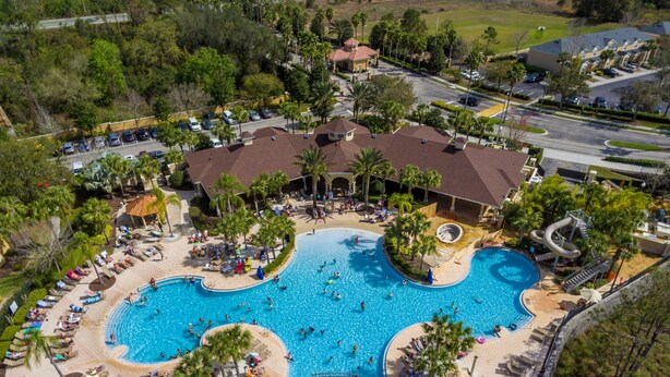 An aerial view of a resort with a large central pool, multiple lounge areas, and a water slide. - Take a look at the reviews! Great value! An awesome place!!! Sleeps up to 16. (Kissimmee)