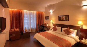 Une chambre d’hôtel avec un grand lit, un bureau, une chaise et un téléviseur.