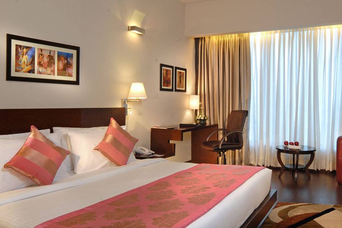 Une chambre d’hôtel avec un grand lit, deux fauteuils, un bureau et une télévision.